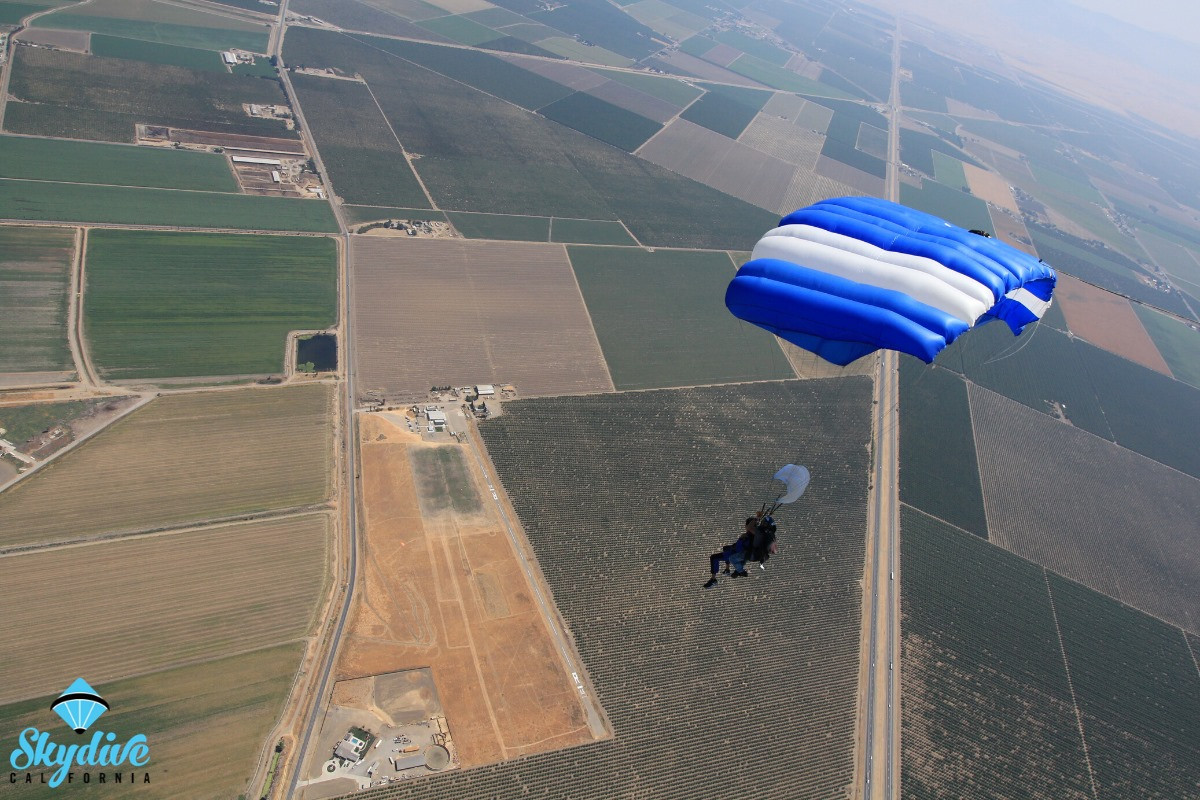 Aerial view of Skydive California, a premier Northern California film location, with a parachute gliding nearby.