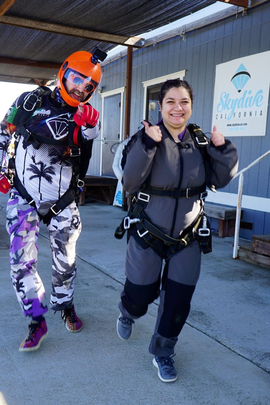 A first-time tandem skydiver walks toward the plane with her instructor, ready for an unforgettable skydiving experience. Skydive Sacramento with us today!