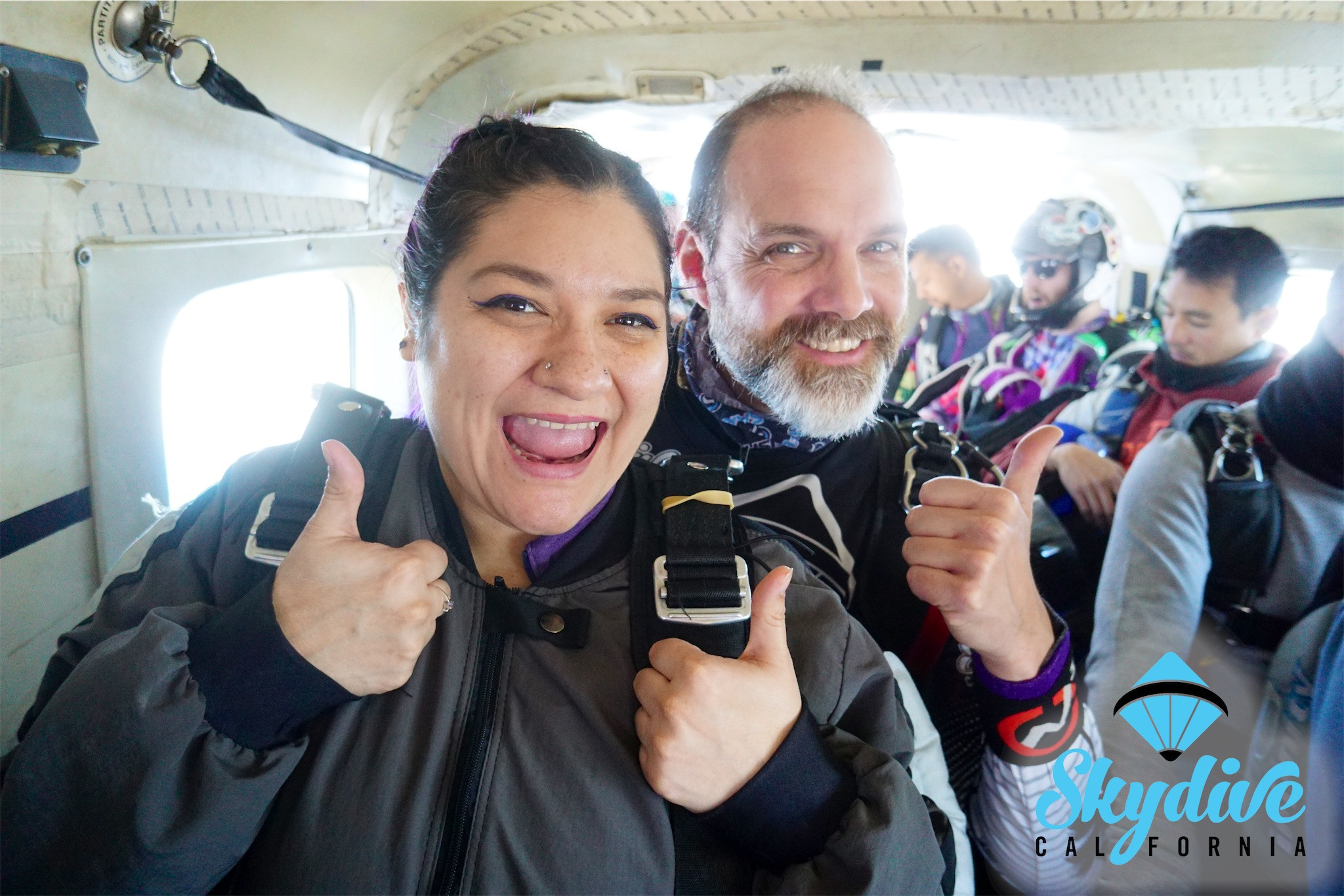 A tandem skydiver and instructor smile and give a thumbs-up before their jump. Looking for the best place to skydive Sacramento? We’ve got you covered!