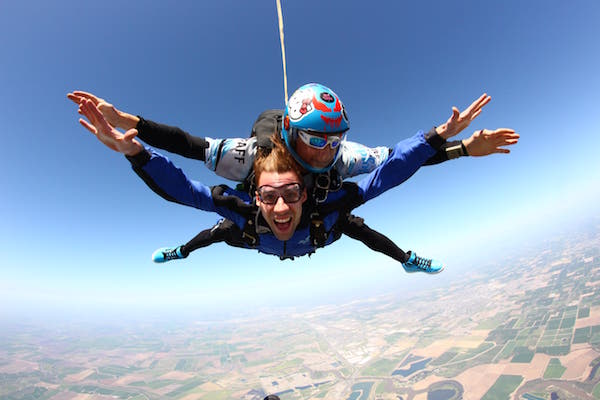 Smiling man in free fall while tandem skydiving
