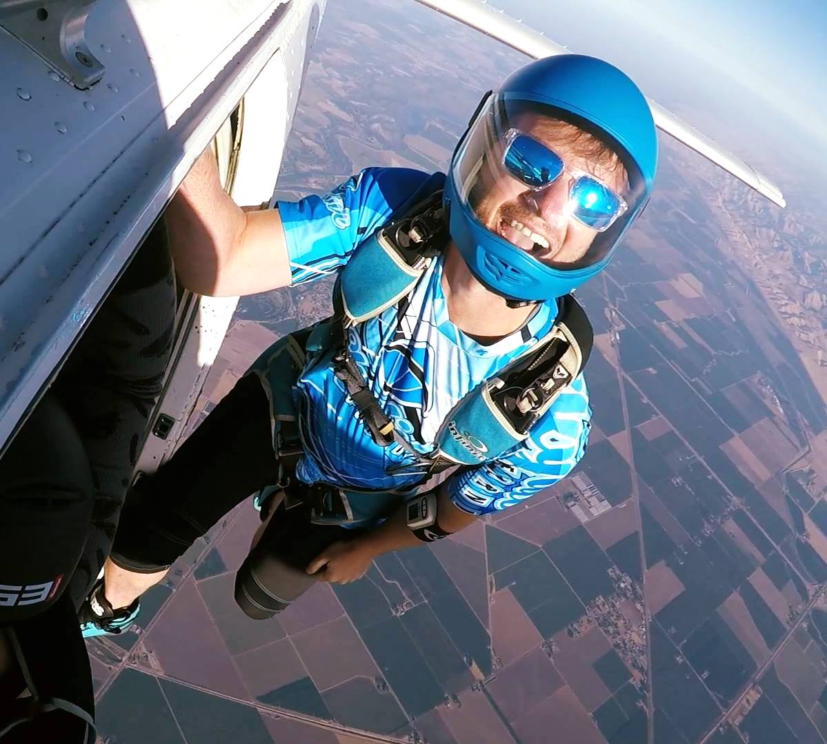 Experienced skydiver hanging off of Skydive California air craft