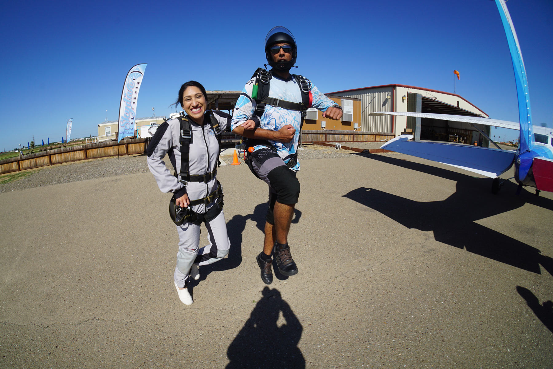 Skydiver and tandem instructor skipping towards the Skydive California airplane.